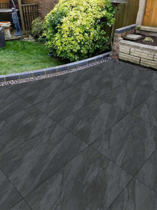 Dark gray tiles on a patio with a garden in the background