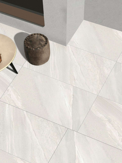 White marble tiles on a floor with a small round stool and table.