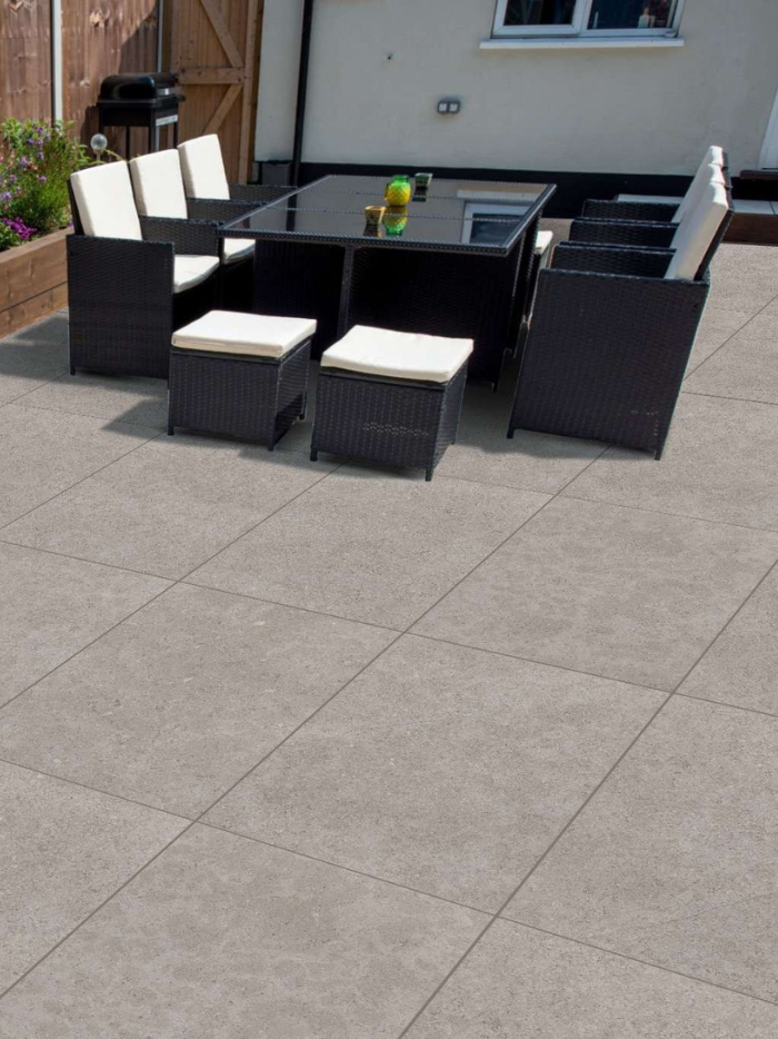 Outdoor patio set with black furniture and white cushions on a tiled patio.