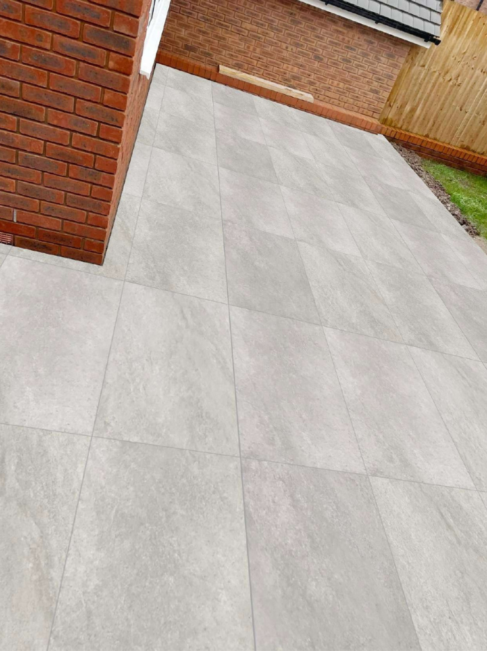 Gray tiled pavement next to a brick wall